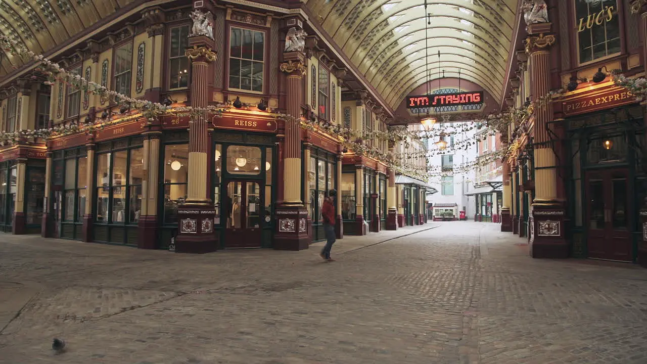 One person walking in an empty street during Coronavirus Covid-19 lockdown in the City of London with quiet roads and shops shut during the global pandemic at Leadenhall Market in England Europe