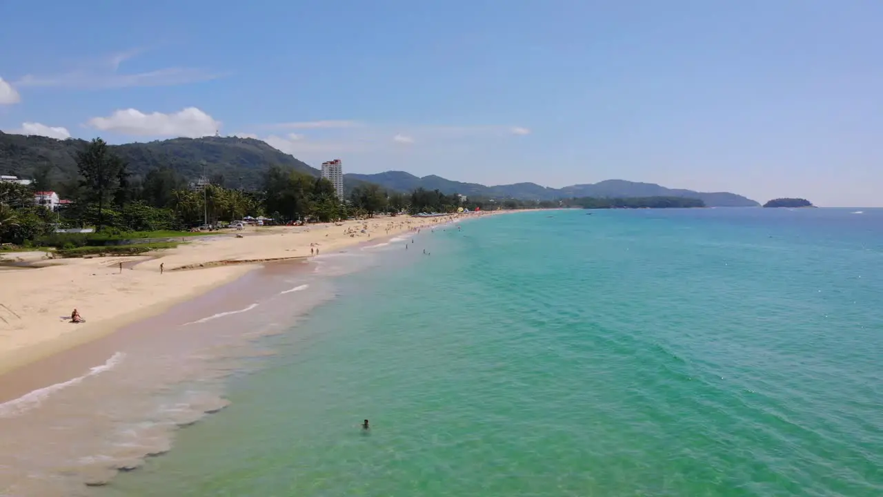 Low aerial drone shot along beautiful sandy coastline of Phuket summer people