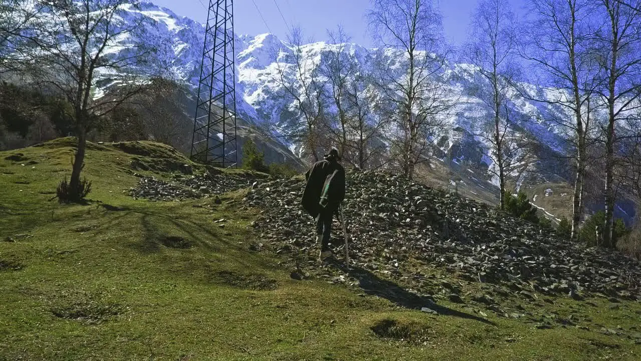 Lonely walking man in mountains with poncho and stick trees snowy mountain aerial view