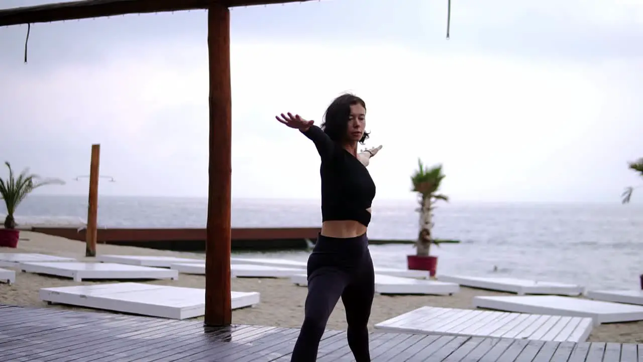 Concentrated Woman Is Doing Yoga On Mat On The Beach The Girl Performs Yoga Stands And Elements Warrior