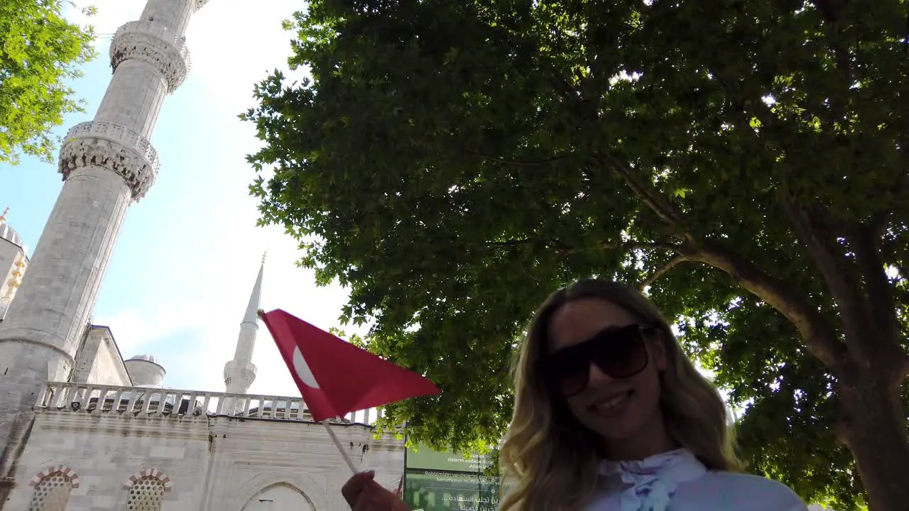 Attractive beautiful girl in shirt waves Turkish flag with view of Sultan Ahmet Mosque in Istanbul Turkey