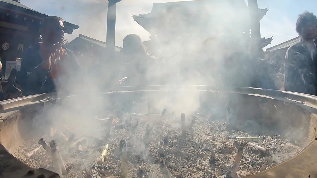 Close-up wide angle view of japanese people worshipping in the smoke of an incense pot in Asakusa Tokyo