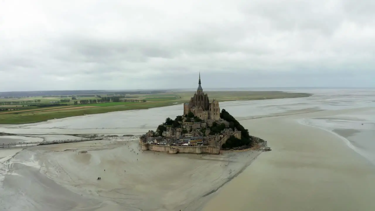 The mont saint Michel drone camera is heading towards the site and there are many tourists