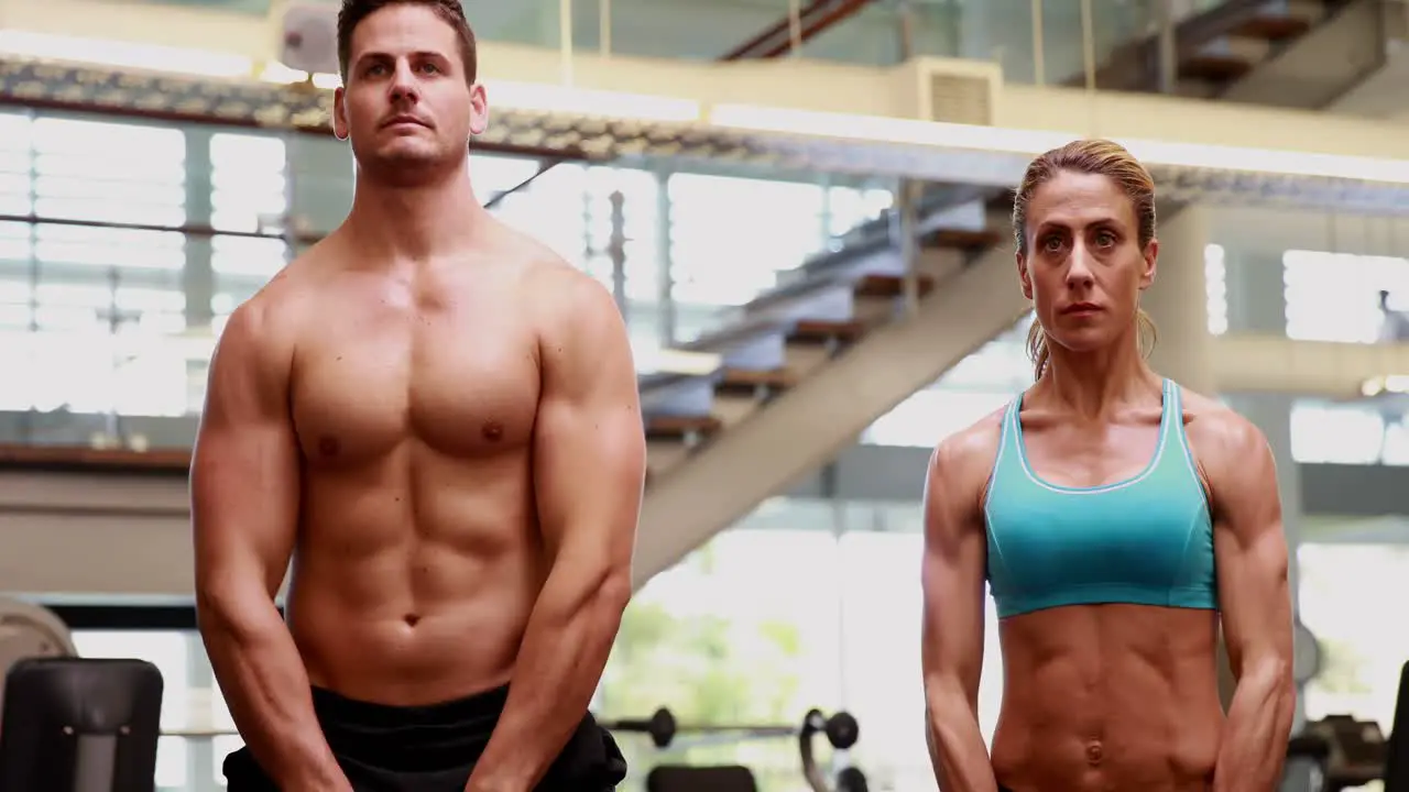 Two fit people lifting kettle bells together