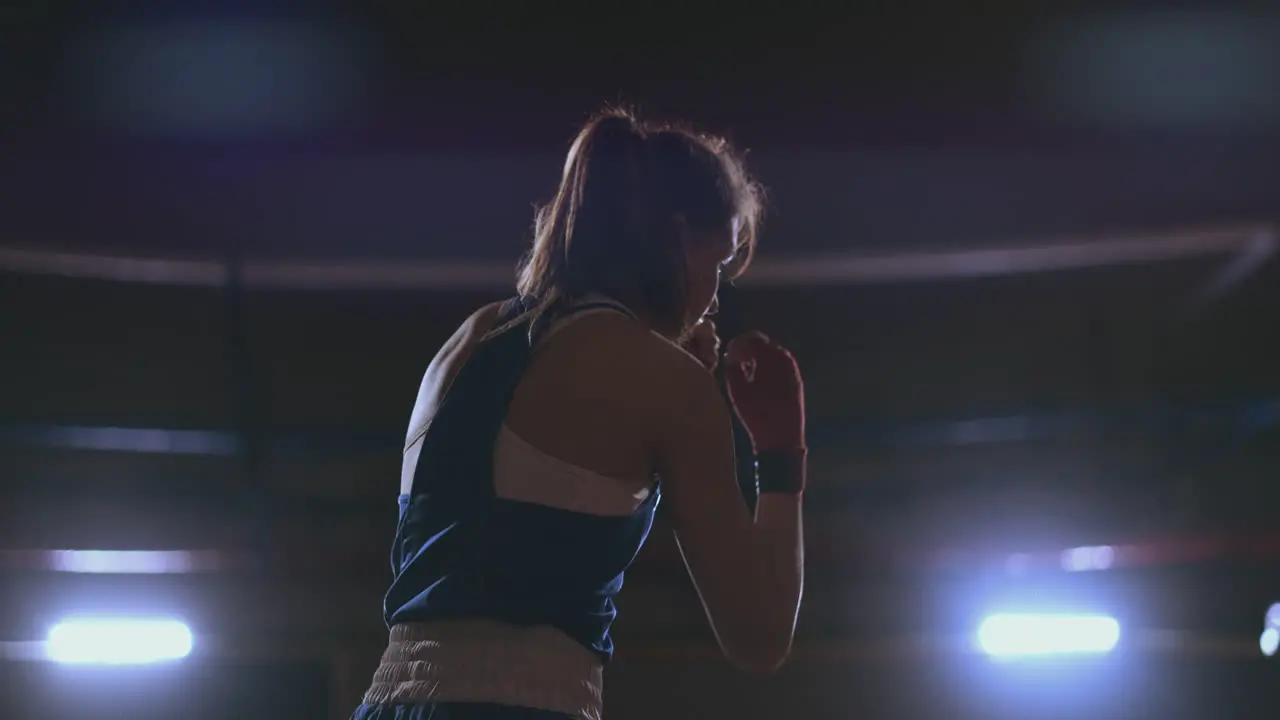 Female boxer training in dark room with back light in slow motion steadicam shot