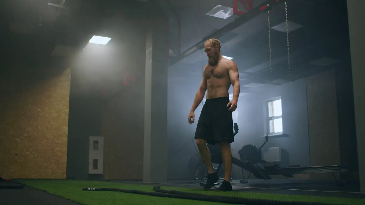 Tired man after training with ropes rests in the training hall in slow motion