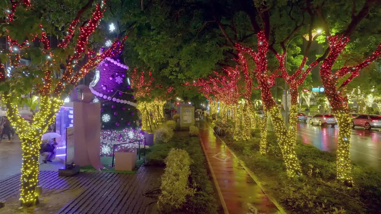 Aerial backwards shot of flashing decorated Christmas trees in city of Taipei at night during rainy day