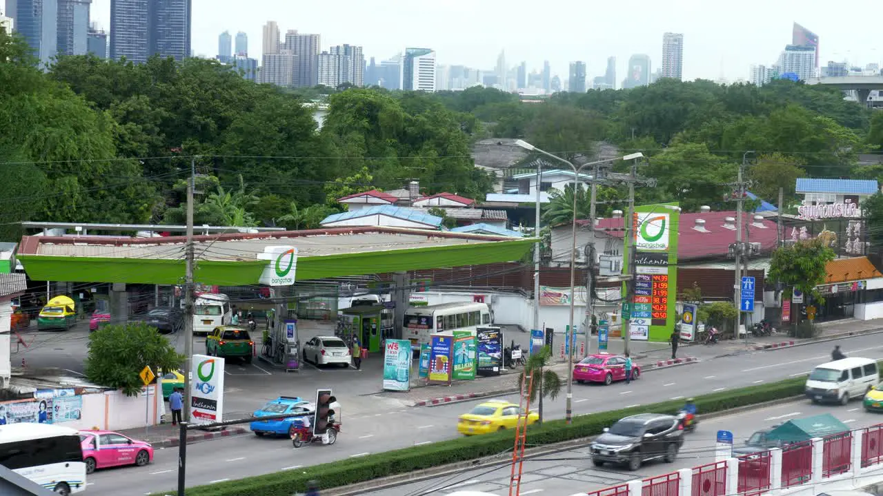 Bangchak Petrol Station with workers filling up the tanks or cylinders as seen from a higher viewpoint in Bangkok while the motorists are passing by on each side of the busy city road