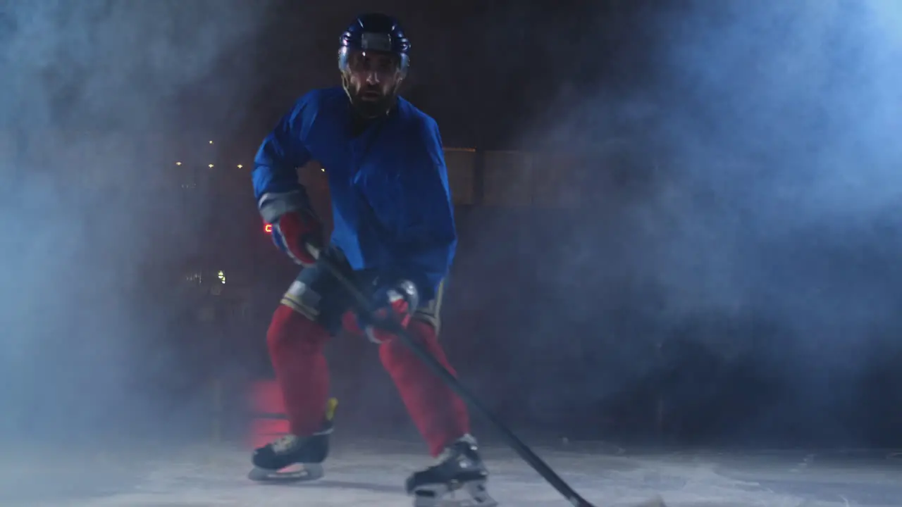 Man hockey player with a puck on the ice arena shows dribbling moving directly to the camera and looking straight into the camera