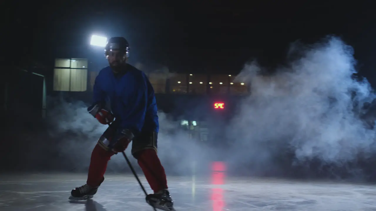 Professional hockey player with a stick accelerates on the ice and stops abruptly in front of the camera looking straight into the camera