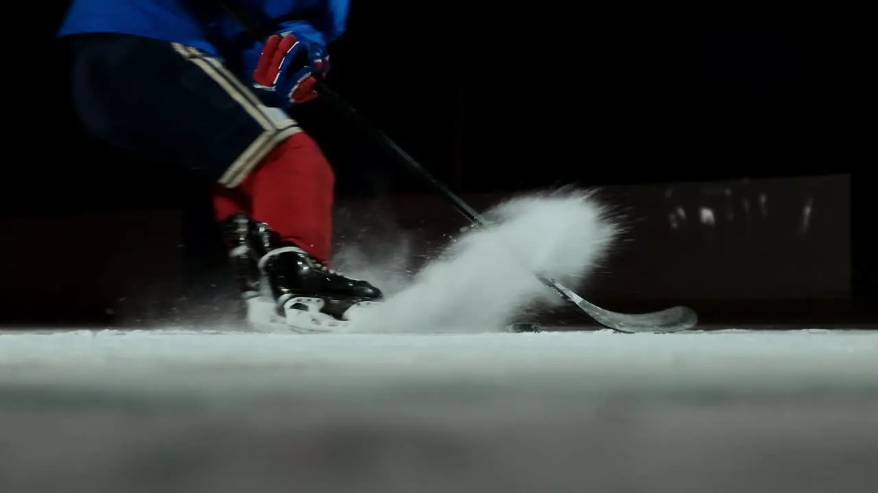 Close-up slow motion hockey puck and flying snow hockey player picks up the puck stick