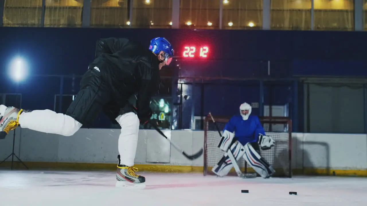 Professional hockey player and goalkeeper train punching puck on goal Goalkeeper and player in training Slow motion