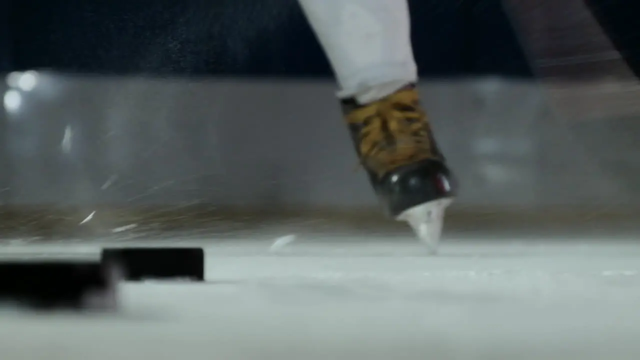 Close-up of the puck on the ice and the hockey player strikes the puck in slow motion