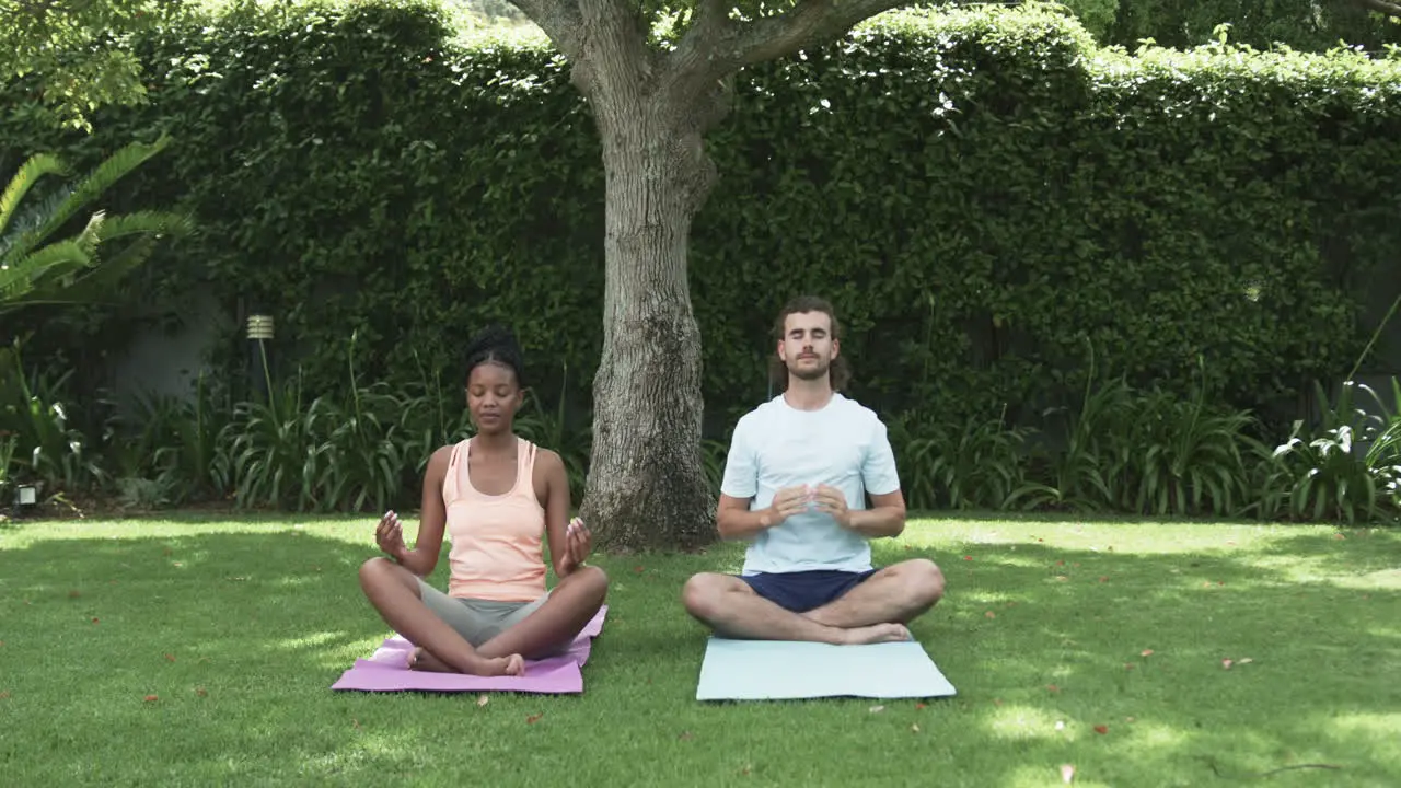 Young African American woman and young Caucasian man meditating outdoors