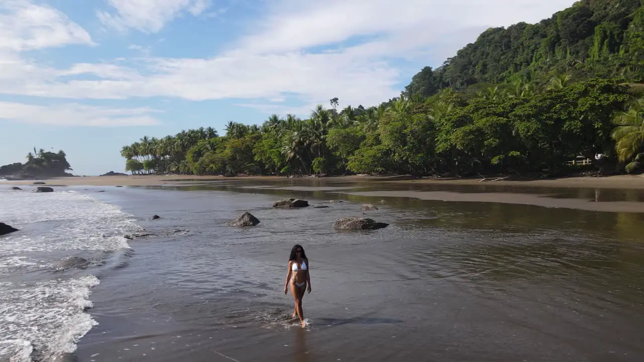 Athletic lady in a bikini walks in the sea on a tropical sand beach