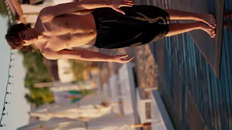 A guy with a naked torso and black shorts stands up straight during his meditation and yoga class on the beach