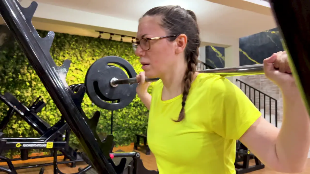 Woman performing squats with a straight bar in gym