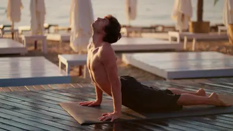 Bare-chested guy took a special strip for yoga and meditation on Sunny Beach in the morning Exercising in the morning on a private beach