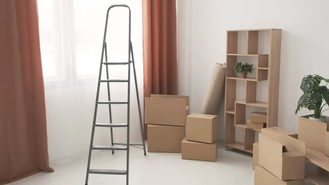 Moving Boxes And Ladder In Empty Room Of New Home 1