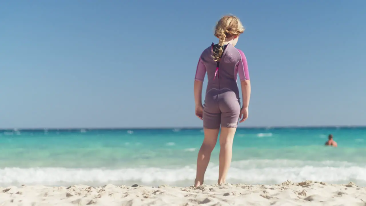 Little girl standing relaxed on the beach by the sea