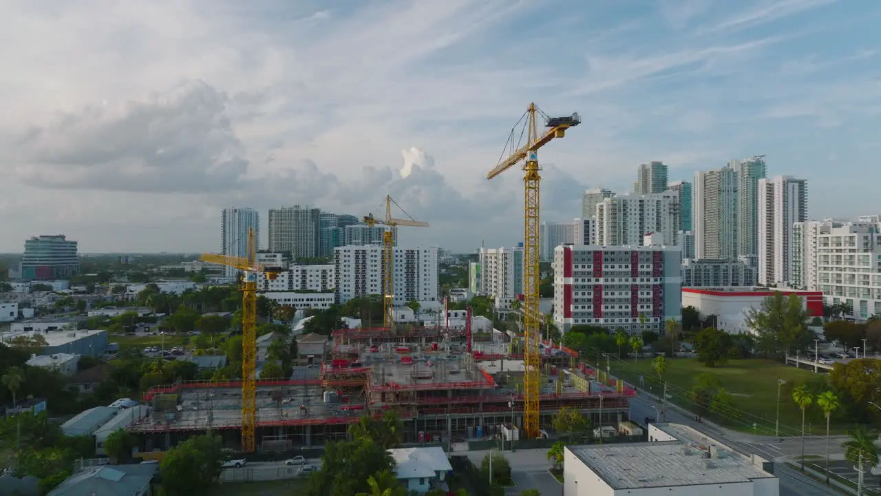 Slide and pan footage of cranes on construction site at twilight urban development in background Miami USA