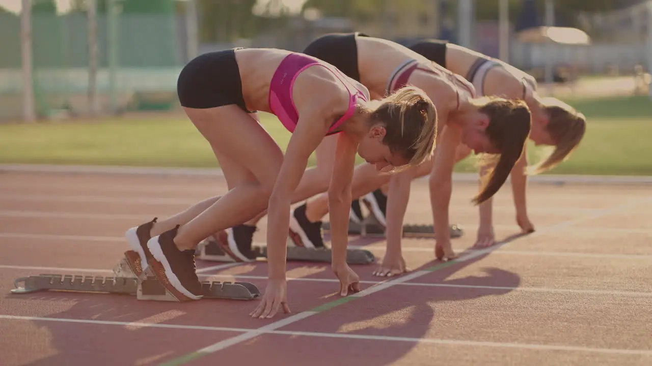 Three female track and water athletes start the race at the stadium in running pads at a sprint distance Women track and track and file runners running in the stadium