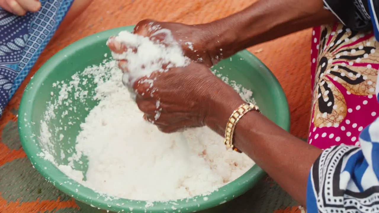 Traditional food preparation hands kneading coconut snow making cocos milk in a bowl