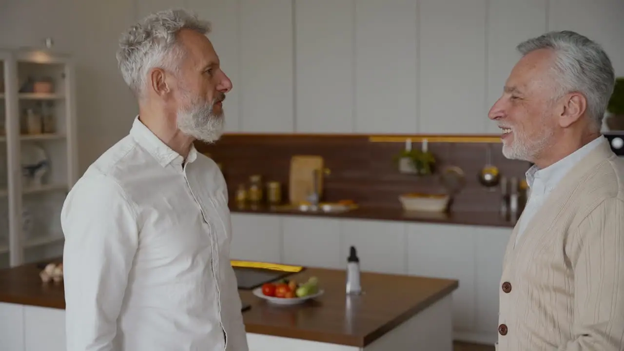 Dos Felices Amigos Mayores Dándose La Mano Y Hablando En Casa