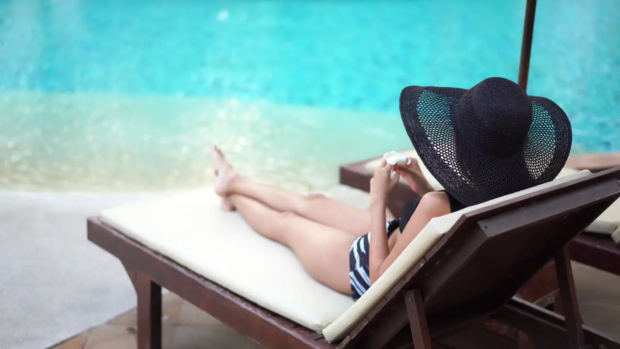 Asian woman sitting in solace on a chaise at the pool