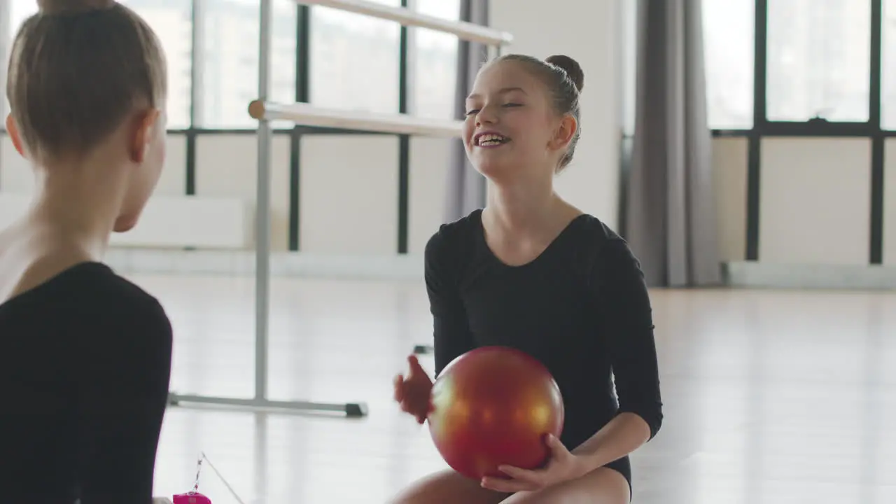 Dos Chicas Rubias Gimnásticas Hablando Y Riendo Mientras Juegan Con Una Pelota Sentada En El Suelo Antes De Comenzar La Clase De Ballet