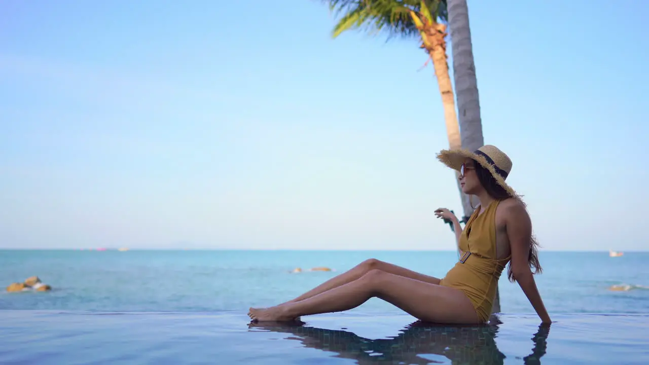 Woman in yellow bathing suit sitting at the edge of a swimming pool