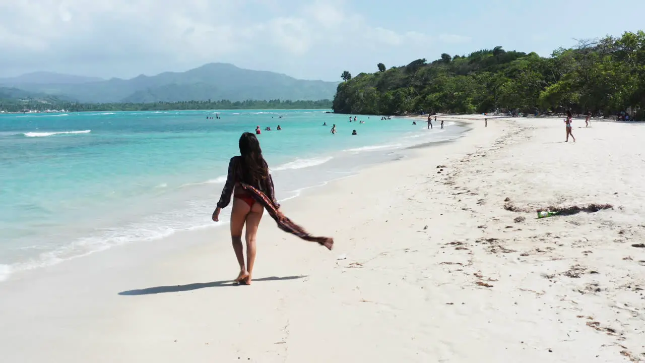 Beachgoer enjoys walk on white sand tropical paradise aerial crane down