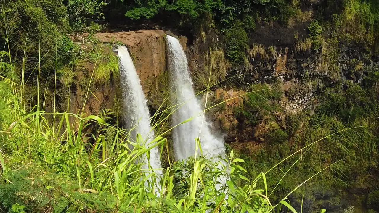 HD Slow motion Hawaii Kauai slow boom up of Wailua Falls with tall grass in foreground