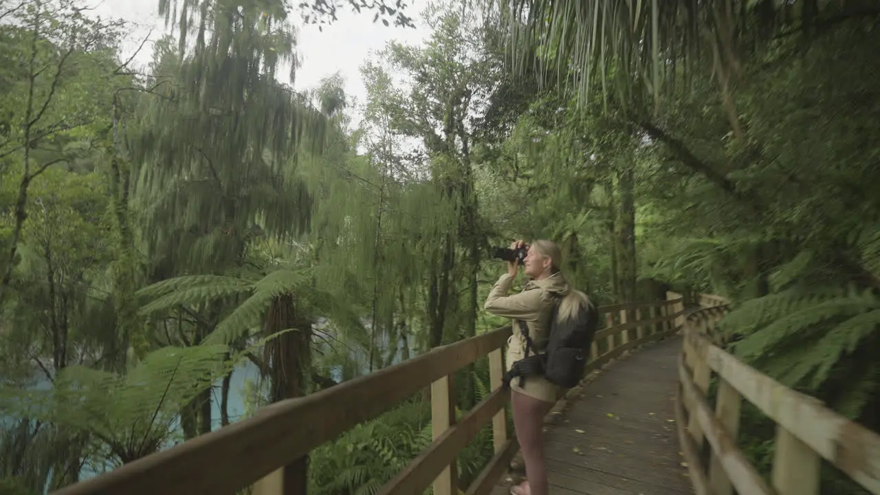 Female hobby photographer taking photos on wooden boardwalk in nature New Zealand