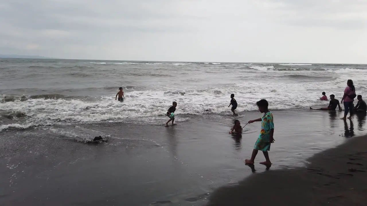 Kids Play with Soccer Ball in the Beach Having fun at the Sea Water of Bali Indonesia Saba Gianyar Black Sand Child Friendship Southeast Asia