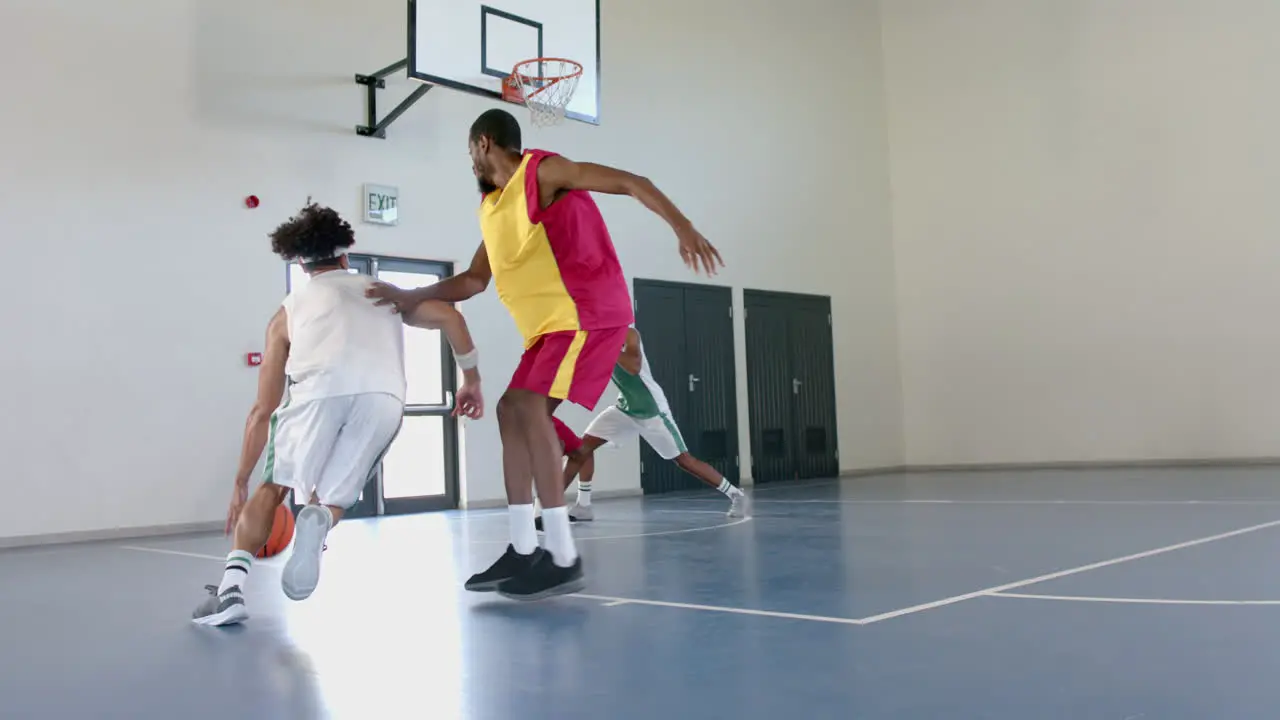 Young African American men play basketball indoors with copy space