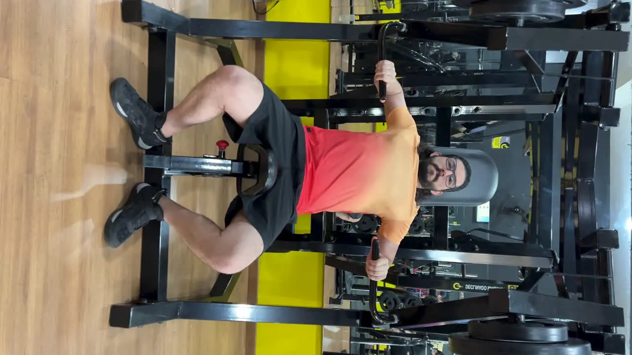 Latin man with beard and long hair performing exercise on equipment declined