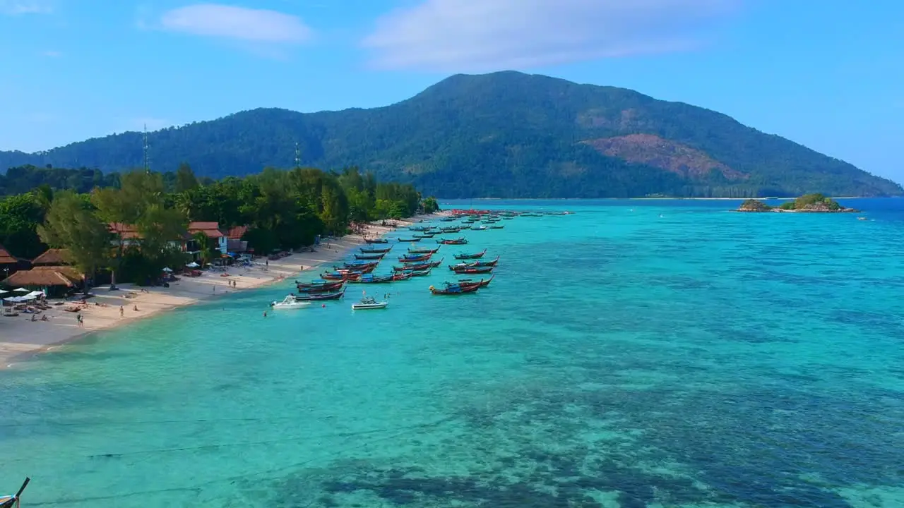 A distance but aerial shot of boats being park with unrecognisable people by the beach