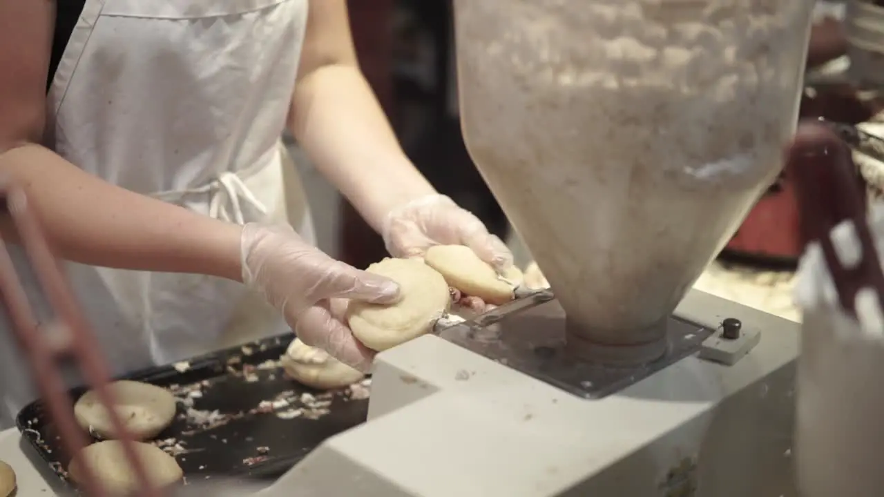 Woman filling donuts with frosting at a donut shop