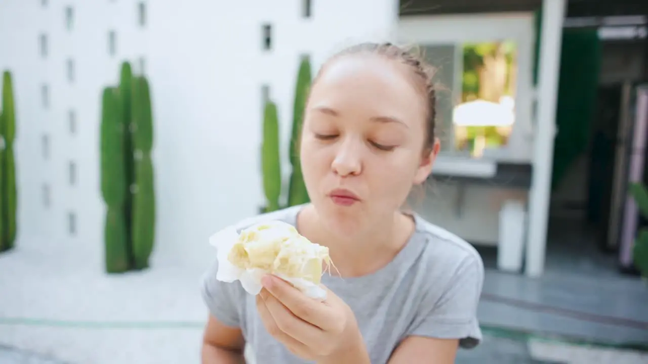 Blonde female eating tasty durian outdoors