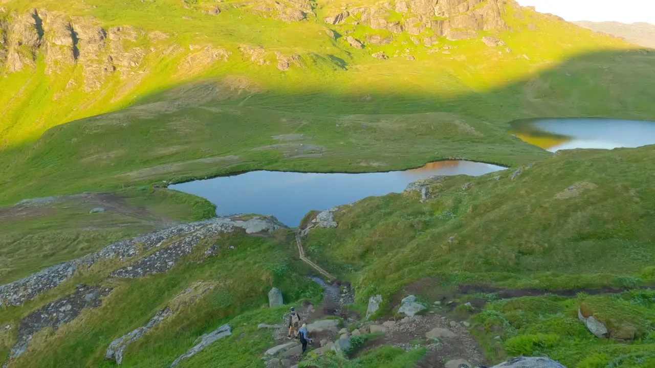 Two tourist walking down the hiking trail in a breathtaking landscape of Lofoten Island