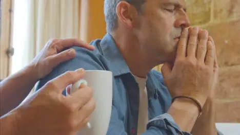 Low Angle Shot Looking Up at Visibly Concerned Middle Aged Man as Wife Tries to Comfort Him