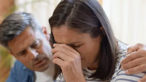 Close Up Shot of Concerned Middle Aged Woman as Her Husband Tries to Comfort Her