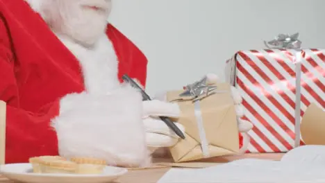 Medium Shot of Santa Sitting at Desk Organising Presents and Gifts