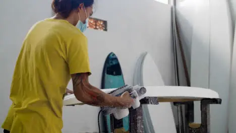 Handheld Wide Shot Revealing a Surfboard Shaper Using Power Tool On Polystyrene Board