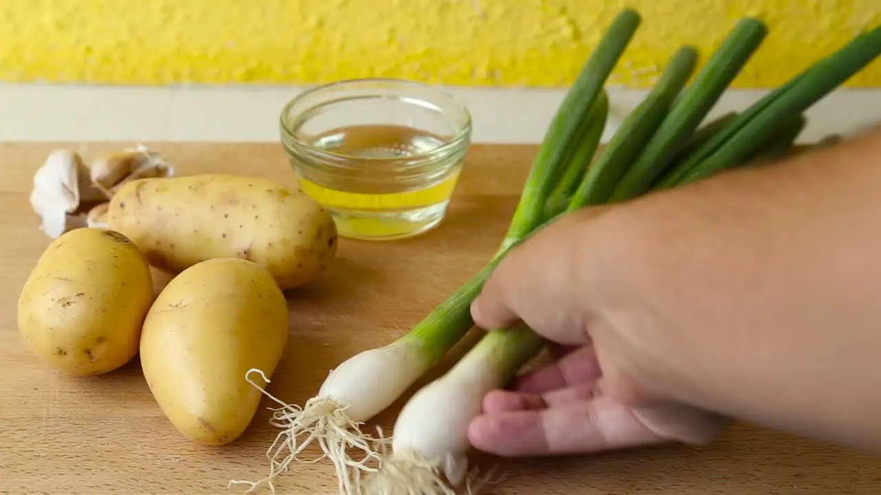 Male Hand putting Green Onion on wooden cutting Board