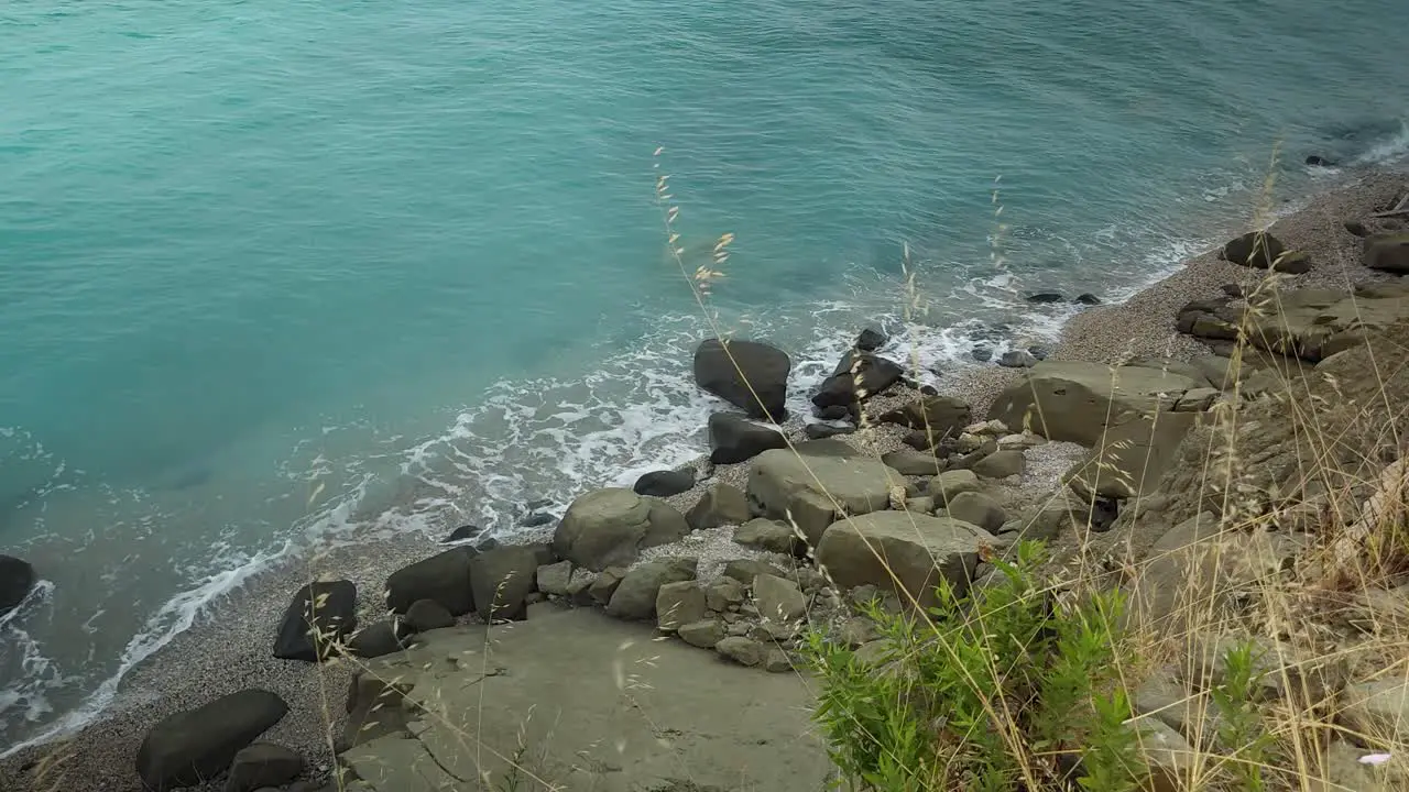 Green coast with beautiful isolated quiet beach and carved cliffs washed by sea waves in Mediterranean