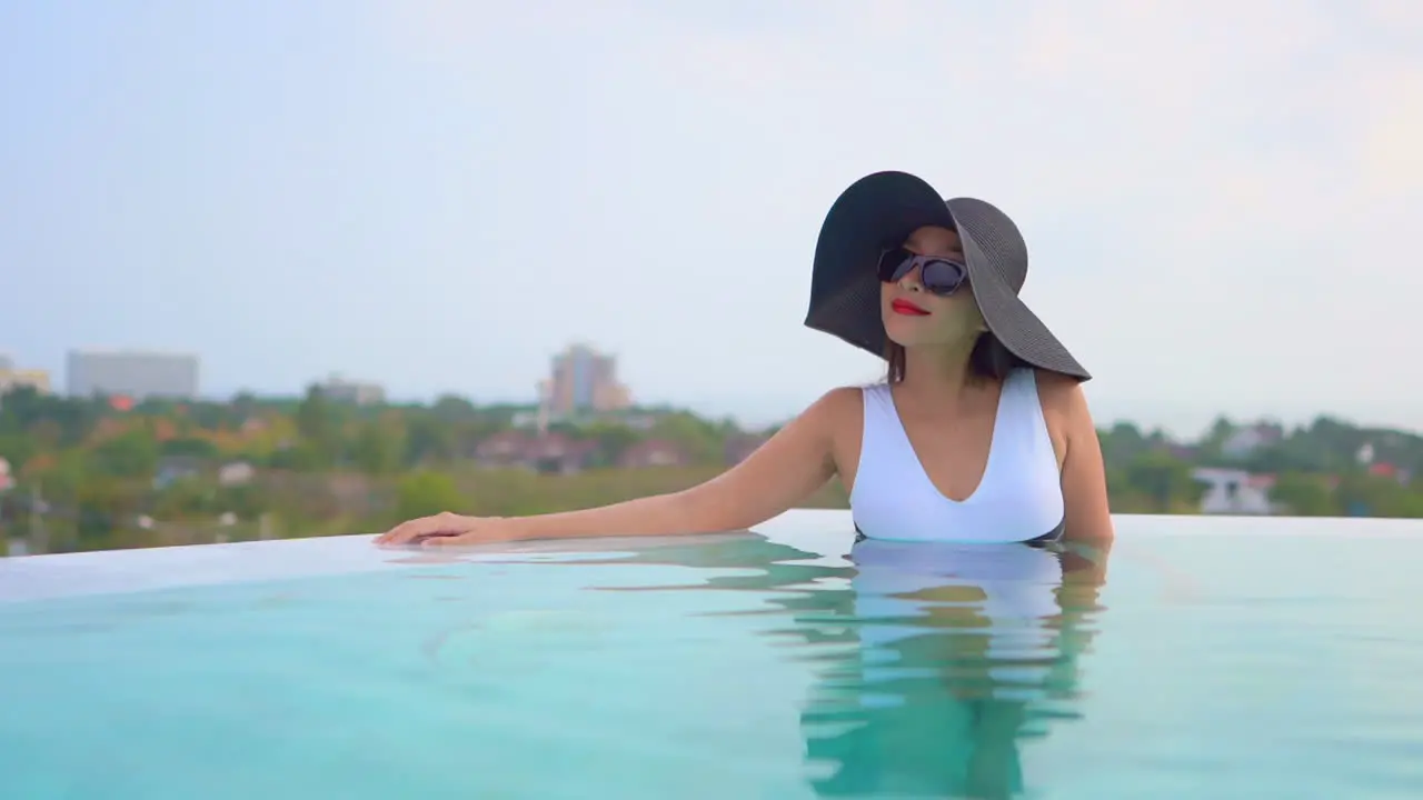 Attractive Asian Female Enjoying in Her Summer Vacation in Pool With Amazing View of Tropical City