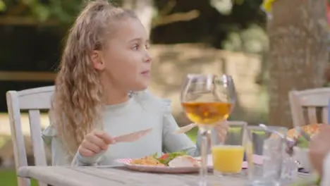 Close Up Shot of Young Girl Eating Outdoor Dinner with Family 