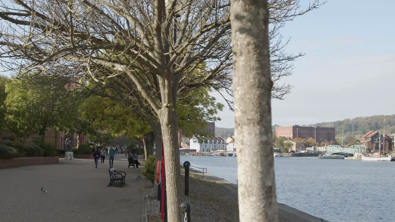 Wide Shot of People Walking Along Waterside Pathway In Bristol England